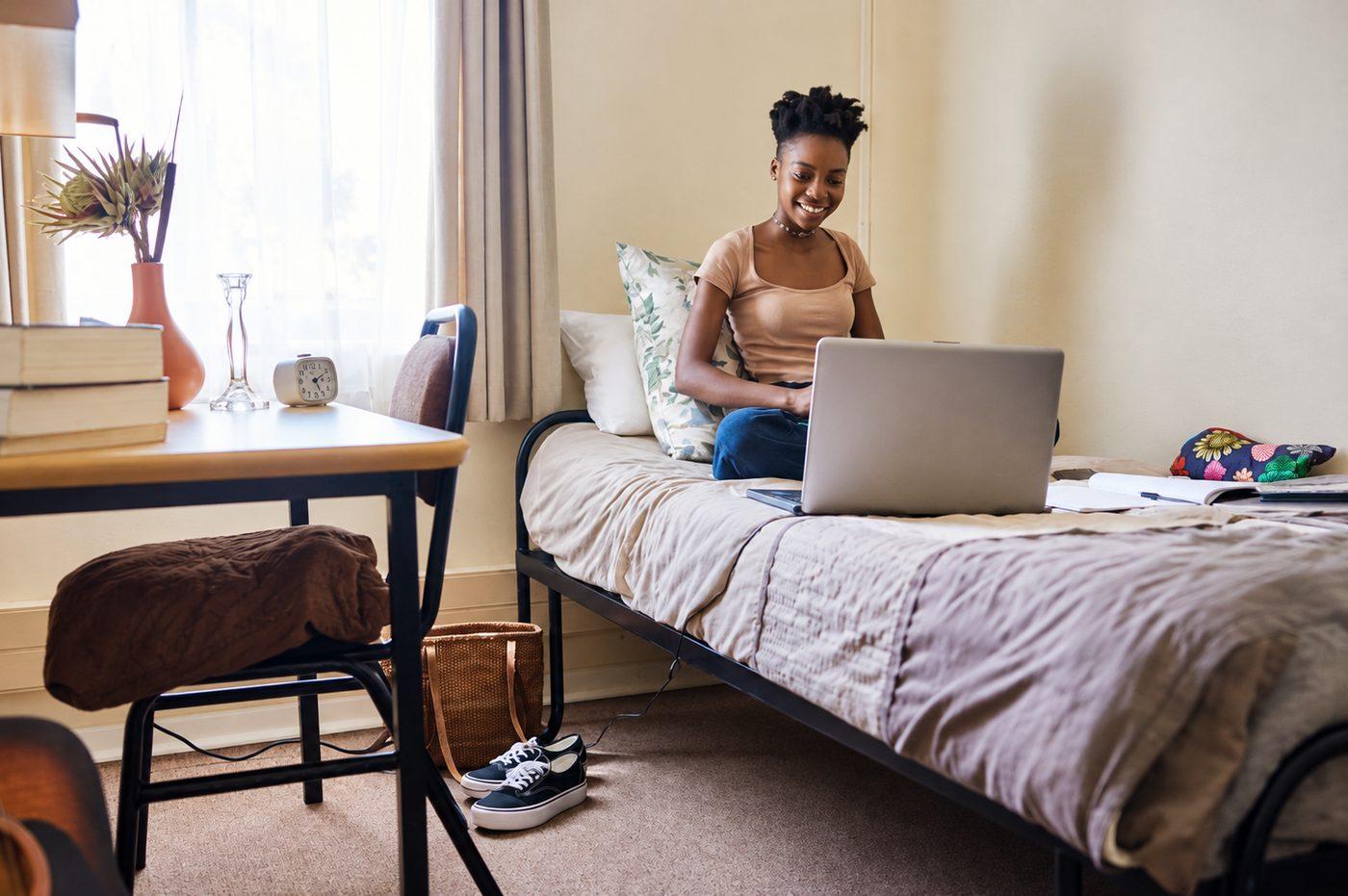 A student working at a laptop in her hostel room